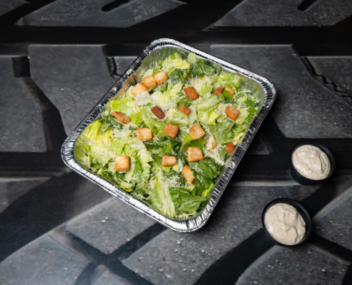 Large portion of leafy green Caesar salad and dressings.