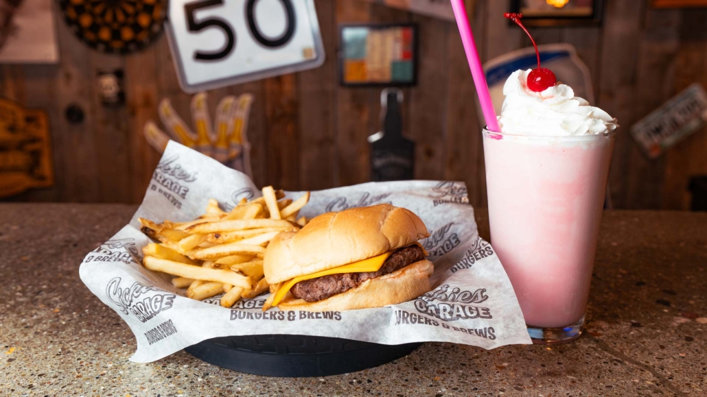 Cheeseburger with American cheese, golden french fries, and a strawberry malt topped with whipped cream
